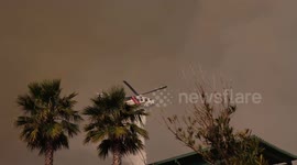 Helicopters dump water on smoldering Palisades Fire in California