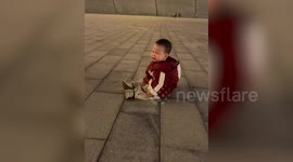 Overdramatic toddler throws himself to the ground after being nudged by toy bike