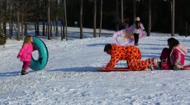 Kids get a big push from their parents or guardians down a snowy hill in Southeast North Carolina, USA
