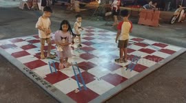 Kids playing wooden giant snakes and ladders chess game outdoor