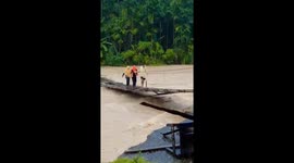 Residents cross rickety wooden suspension bridge to flee floods in Indonesia