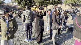 Tourists wear virtual reality glasses that display a reconstruction of the ancient square in front of the Colosseum in Rome.