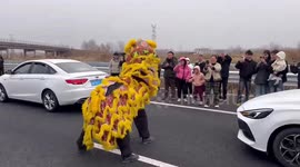 Young men perform lion dance for motorists stuck in traffic in China