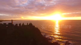 Beautiful sunset with ocean glitter path over Dunluce Castle in Northern Ireland