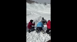 Friends help snowboarding beginner to get a perfect winter holiday money shot