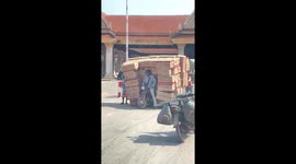 Motorcycle rider struggles with dozens of boxes stacked on his bike