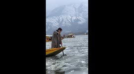 People row boats in frozen Dal Lake in India