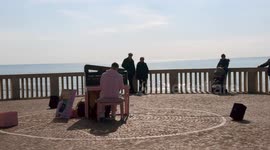 A man in a pink tracksuit plays the piano facing the sea on the Lido di Ostia pier on a sunny February morning in Rome.