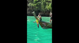 Tourist playfully sits on front of boat like a pirate on Thai island