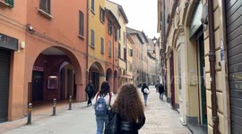 Coming and going of people in a small street in the city center on a gloomy November morning in Bologna.