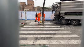 A worker is lowered below street level during maintenance work on water mains in Rome.
