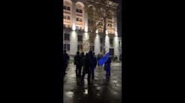 Woman holding EU flag stands in from of riot police in Tbilisi amidst protests against the government