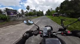 Motorbike rider almost collides with oncoming scooter rider switching lanes