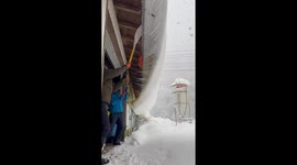 Residents remove huge slab of snow hanging from roof