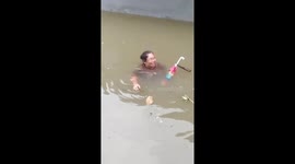Mother holds her umbrella while trapped in neck-deep flood