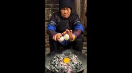 Elderly woman cooks goose egg using hot charcoal in China