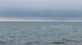 A sailboat navigates off the coast of Lido di Ostia in calm seas on a cloudy December day in Rome.