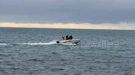 Two people on a motorboat navigate off the coast of Lido di Ostia in calm seas on a cloudy December day in Rome.