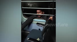 Stowaway clinging to moving train tries reaching inside for valuable items in India