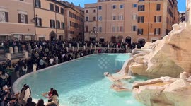 Overview of the Trevi Fountain and the square in front full of tourists on a bright February day in Rome.