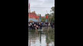 People participate in the challenge of walking on bamboo trees across the lake during the Lunar New Year Festival in Vietnam