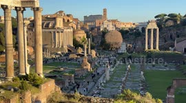 Tourists in the valley of the Roman Forum and the Colosseum in the background on a clear December afternoon in Rome.