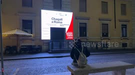 A woman with a backpack and ear muffs for the cold sits on a bench in front of the official Jubilee information point on Christmas Eve in Via della Conciliazione in Rome.