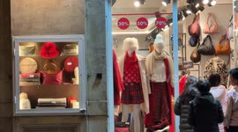 People walk into a clothing store promising various discount levels on Christmas Eve in Rome.