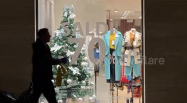 People pass in front of a clothing store that promises sales with heavy discounts on Christmas Eve in Rome.