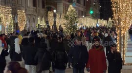 A crowd of people strolling along Via Ottaviano decorated with Christmas lights on the evening of Christmas Day in Rome.