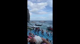 Tourists cling to floating pontoon being rocked by choppy sea