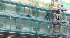 Construction workers wearing safety helmets work on scaffolding during the renovation of a building facade in central Rome.