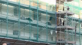 Construction workers wearing safety helmets work on scaffolding during the renovation of a building facade in central Rome.