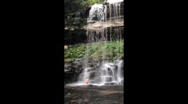 Un monaco che medita sotto l'acqua di una cascata, in un bosco sperduto della Cambogia