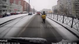Biker delivery guy falls off while using feet to brake on snow covered road
