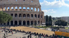 Wide shot of the Colosseum square with tourists without the barriers of the Metro C works with the Colosseum in the background and seagulls flying on a clear February day with spring temperatures in Rome.