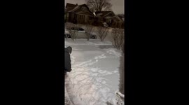 Dog playfully interrupts man shoveling snow in Waukegan, Illinois, USA