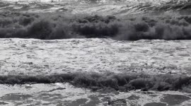 The motion of the waves of the very rough sea with reflections of the sun on the coast of Lido di Ostia in Rome.