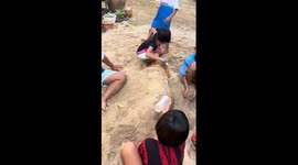 Kids cover dog with sand in playful moment in Phuket, Thailand