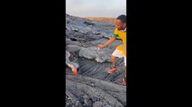 Man lights cigarette on molten lava from Erta Ale volcano in Afar, Ethiopia