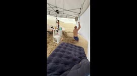 Beachgoers cling onto their canopy to prevent wind from blowing it away