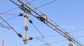 Man climbs high-voltage transmission line at train station, rescued