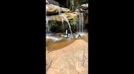 Person slips while walking under a waterfall in Kenya