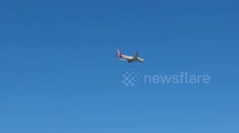An American Airlines plane flies through the blue sky as it prepares to land at Fiumicino Airport and is about to fly over some buildings in Rome.
