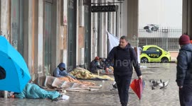 Coming and going of Roman citizens and tourists in front of the homeless who bivouac in the camp built under the porticoes overlooking Piazza dei Cinquecento, in front of Termini station in Rome.