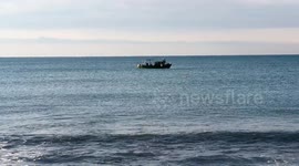 A small fishing boat with calm seas and clear skies off the coast of Lido di Ostia in Rome.