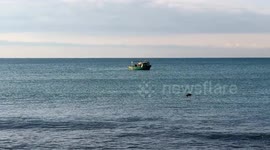 A small fishing boat with calm seas and clear skies off the coast of Lido di Ostia in Rome.