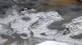 Mesmerising water flowing under ice on a Scottish river during winter.