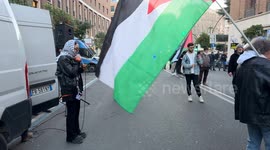 A protester wearing a Keffiyeh shouts 'Free Palestine' (in Italian) into a microphone, with police officers in the background lining up to delimit access to the US Embassy while waving the Palestinian flag during the demonstration organized by the Italian