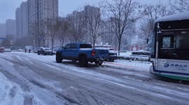 Pickup truck pulls a stuck bus on a slippery road in Shandong, China